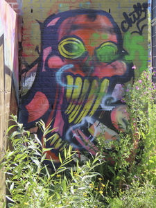 901825 Afbeelding van een graffitikunstwerk van een jongeman met grote pet op een van de muren rond de tijdelijke ...
